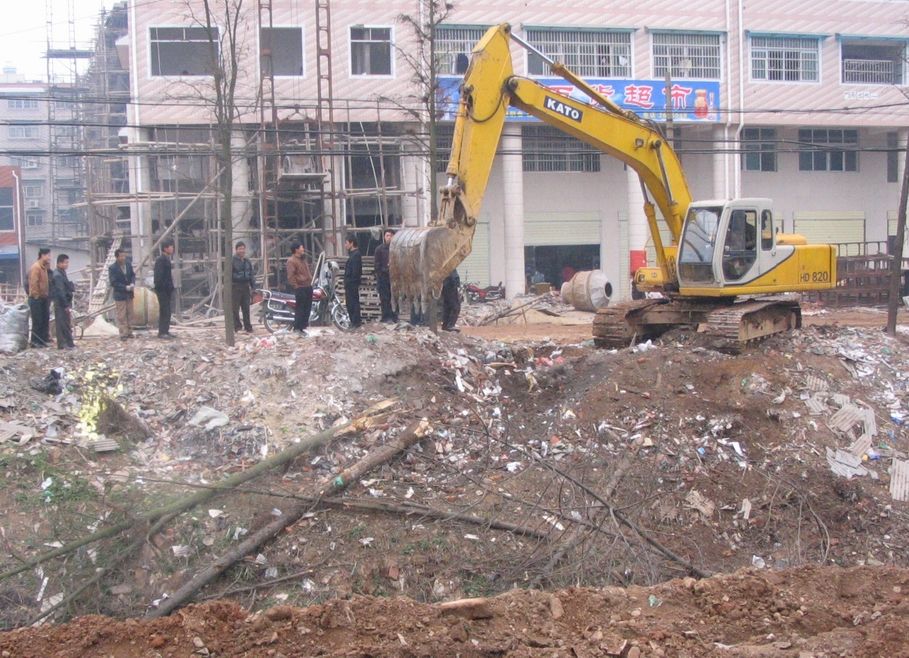 People watching an excavator clear a construction site in Zhuzhou, Hunan